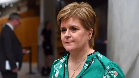 Nicola Sturgeon, wearing a green top, and a gold necklace in the Scottish Parliament 