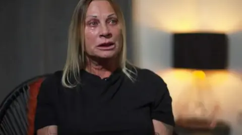 BBC Crimewatch Tracey McCafferty sat in a chair and wearing black. She is looking away from camera and is crying.