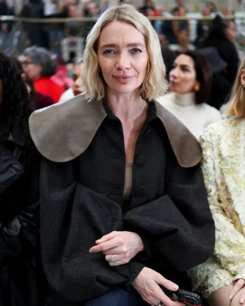 Isabel Infantes/Reuters Jodie Kidd, a woman with blonde hair, sits in an audience in a black cape