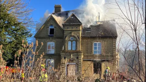 Bedfordshire Fire and Rescue Service A large Victorian house in yellow/grey brick, with smoke billowing from the roof