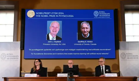 Getty Images A screen shows the laureates of the 2024 Nobel Prize in Physics, US physicist John J Hopfield (top L) and Canadian-British computer scientist and cognitive psychologist Geoffrey E Hinton as (bottom LtoR) Chair of the Nobel Committee for Physics Ellen Moons, Secretary General of the Royal Swedish Academy of Sciences Hans Ellegren and Member of the Nobel Committee for Physics Anders Irbaeck make the announcement at the Royal Swedish Academy of Sciences in Stockholm, Sweden on October 8, 2024. American John Hopfield and British-Canadian Geoffrey Hinton won the Nobel Prize in Physics on October 8, 2024 for pioneering work in the development of artificial intelligence