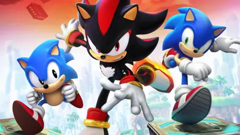 Sega Sonic, um personagem de desenho animado mascote ouriço azul, correndo em direção ao espectador. Ao lado dele está uma versão mais antiga do Sonic, assim como Shadow, um personagem ouriço preto.