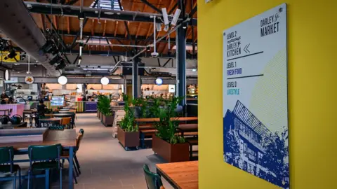 Bradford Council Inside Darley Street Market, showing tables and benches with a kitchen in the background