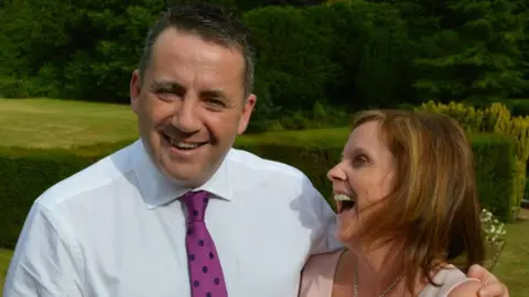 Supplied John Hunt in a white shirt, smiling, as his wife looks towards him as she laughs