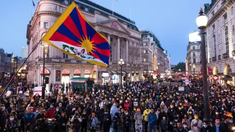 Getty Images Protesters seen gathering at Piccadilly Circus during the demonstration with a Tibetan flag flying in the foreground.