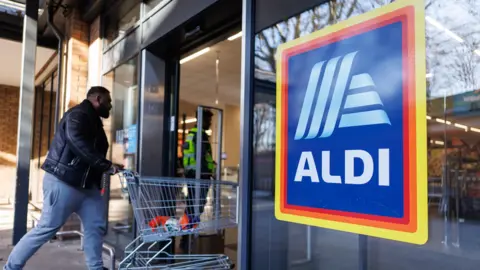  A person with a shopping trolley arrives at an Aldi supermarket