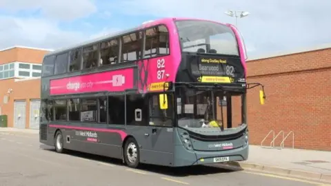 West Midlands Combined Authority A dark grey double decker bus with a pink banner with West Midlands branding
