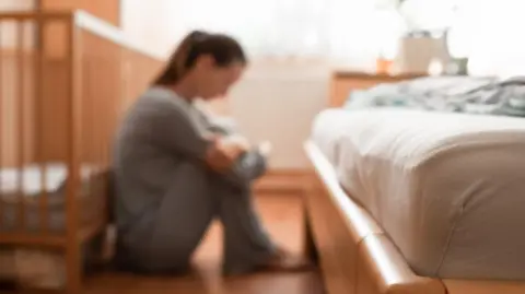 Kieferpix/iStock/Getty Blurred image of woman sat on the floor near a cot and a bed
