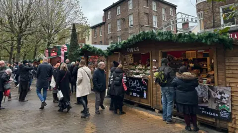 Crowds browse goods in wooden stalls during York's Christmas market.