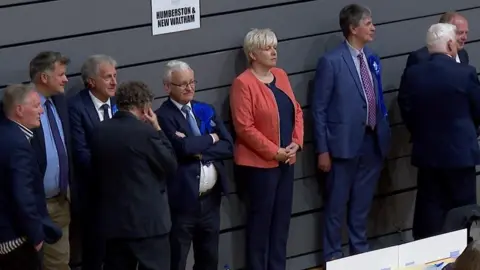 BBC Conservative MPs Lia Nici and Martin Vickers looking unhappy standing against a wall with other candidates