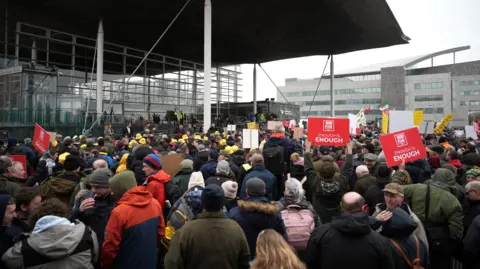 Getty Protesters holding placards gather outside the Senedd on February 28, 2024.