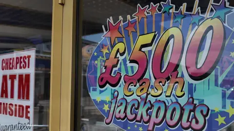 Advertising on the front of a Adult Gaming Centre with the words '£500 cash jackpots and 'cheapest ATM inside'
