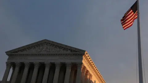Light from the rising sun hits a flag at the U.S. Supreme Court building at the start of the day in Washington, DC.