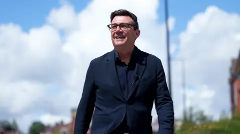Andy Burnham smiles during a campaign visit to Ashton-in-Makerfield before the forthcoming by-election, in Manchester, England, Tuesday, June 9, 2026. 