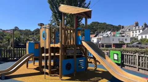 A picture of St Aubin play area. There is a number of slides and a section for children to climb.