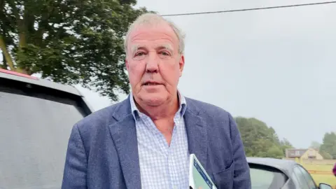 PA Media A man with white hair in a blue suit and checked shirt