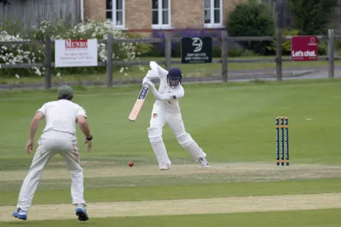 Evan Hill A left-handed batsman hitting a ball towards an offside fielder.