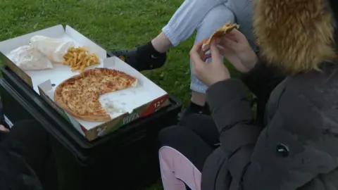 Children eating pizza in the rain