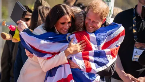 PA Media The Duke and Duchess of Sussex and Lisa Johnston