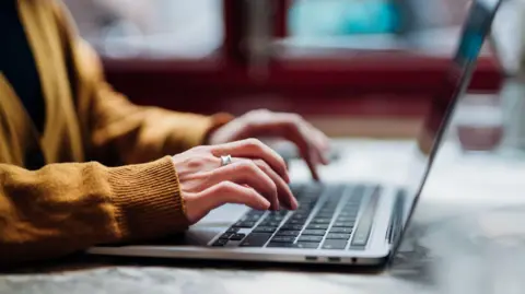 Getty images a woman - an anonymous in the image and only her arms and hands can be seen - type on a laptop