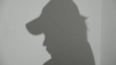 A silhouette of the victim wearing a baseball cap
