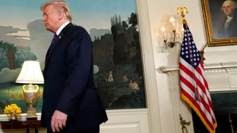 Reuters Donald Trump walks out of frame, left, off-centre, with the White House decor and US flag in the background