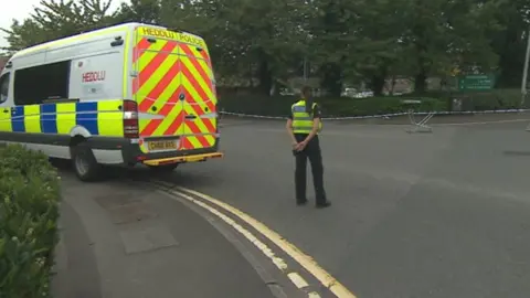 BBC A police officer and police van outside a crime scene