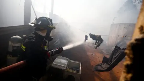 Reuters A firefighter tackles a blaze in Valparaíso. Chile. Photo: 24 December 2019