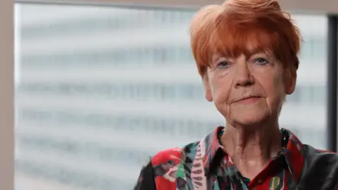 Criminal Cases Review Commission Criminal Cases Review Commission Dame Vera Baird with short red hair wearing a red pink and green patterned blouse. She looks impassively at the camera. She is in front of a blurred out window.
