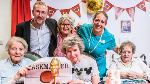 Taskmaster host Alex Horne with (back row left to right) Linda and CareUK Lifestyle Lead Helen (front row left to right) residents Ruth, Chrissie and Diana, at Seccombe Court care home in Adderbury.