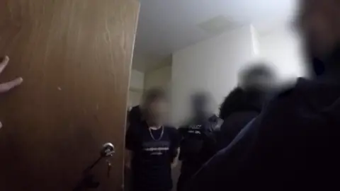 National Crime Agency Body worn footage of a man being arrested. He has several police officers around him and all faces are blurred