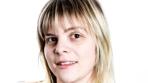 Michelle Monnes-Thomas Michelle has long blonde and brown hair and a fringe. She is smiling at the camera in a tight headshot.
