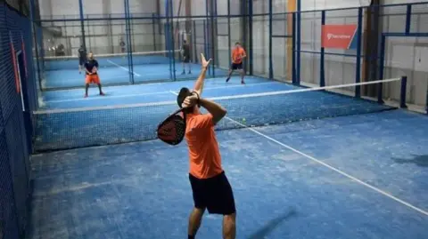 Getty Images Men playing padel on a blue indoor court.
