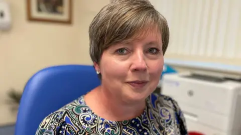 BBC Dr Siaron West sitting at her desk