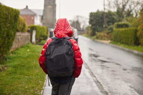child walking to school wearing a coat in the rain