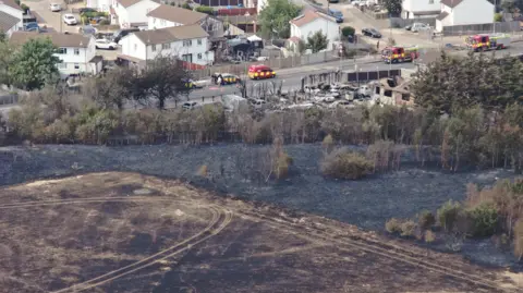 London Fire Brigade Blackened field and burnt buildings next to urban area