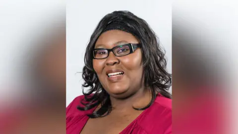 Contributed Sonia Hazel smiles and looks at the camera. She wears glasses and a red shirt. 