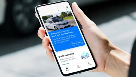 Waymo Person holding phone with Waymo app on