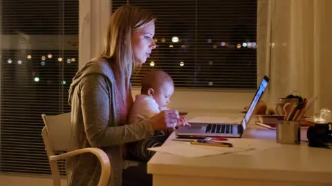 Getty Images Mother with son in the arms, working on laptop