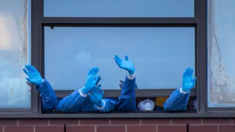 Getty Images NHS staff wave out a window