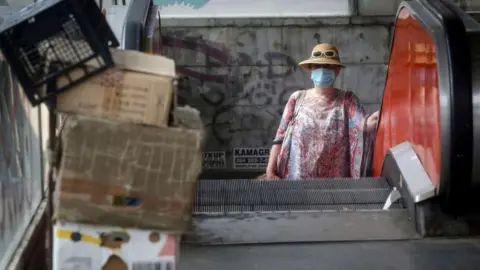 Getty Images A woman in a face mask on an escalator in Belgrade