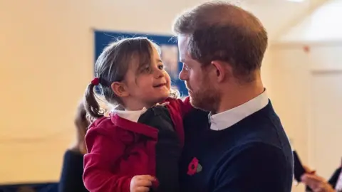 Reuters Prince Harry picks up a little girl at Windsor's Broom Farm Community Centre