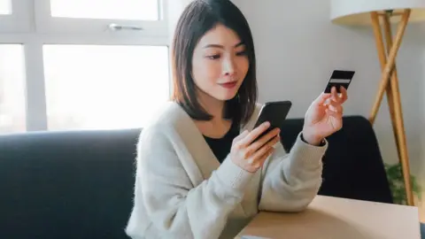 Getty Images Woman shopping online with credit card