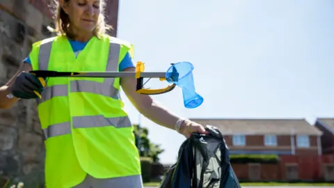 Getty Images Woman picking up litter