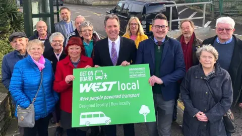 Image of Dan Norris and local residents. Mr Norris is holding a green sign which promotes the WESTlocal scheme.