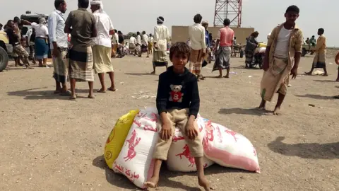 Getty Images Displaced Yemenis receive food aid donated by a British organisation in Yemen's western province of Hodeida