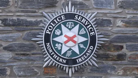 The Police Service of Northern Ireland badge on a stone wall. 