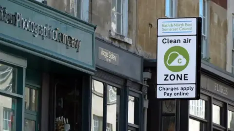 A sign for a Clean Air Zone in front of a row of shops