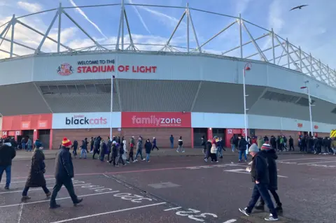 Sunderland AFC home ground, The stadium of light, on a sunny Saturday afternoon in the winter. Fans are arriving ahead of a game, wearing coats and hats