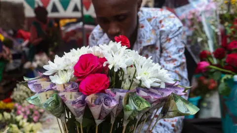 LightRocket via Getty Images A Kenyan businessman prepares a money bouquet made up of Kenya shillings mixed with fresh flowers for a customer during Valentine's day 